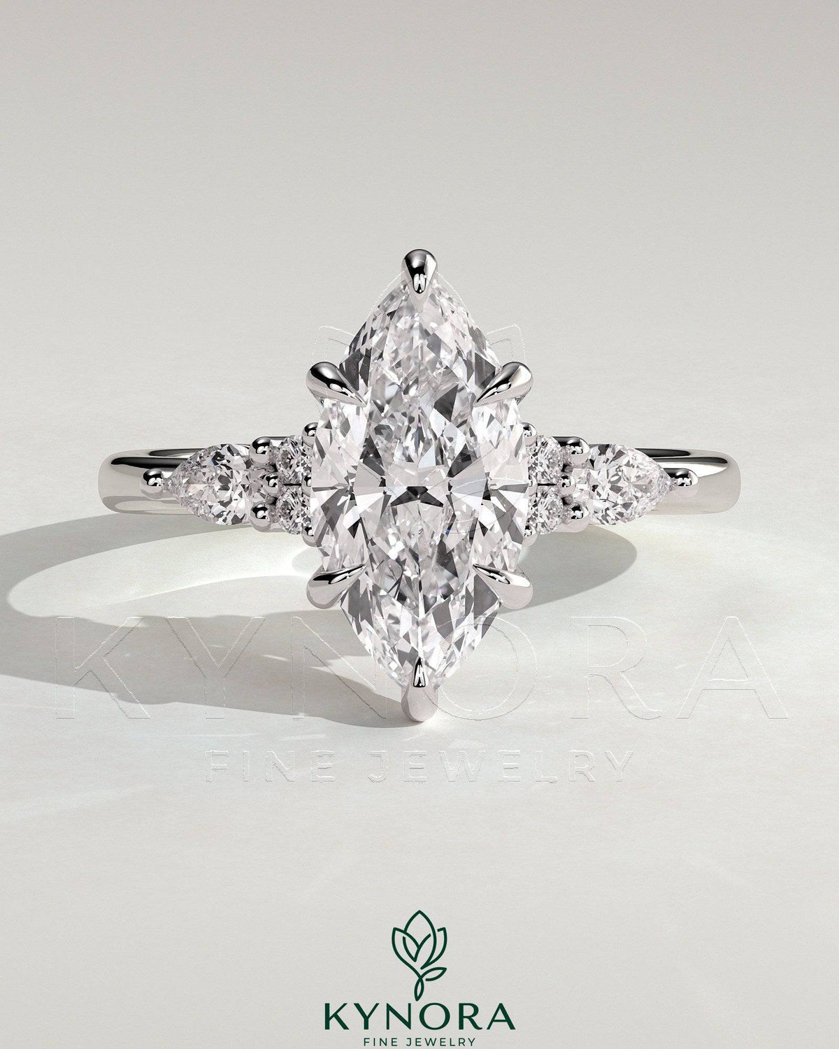 Kynora CJ three-stone engagement ring with 2ct marquise claw solitaire, pear accents, and round shoulder stones.