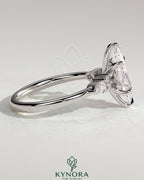 Kynora CJ three-stone engagement ring featuring a 2ct marquise claw solitaire with pear-shaped and round shoulder accent stones.