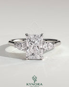 Kynora CJ 2ct radiant claw trilogy engagement ring with pear side stones and cathedral setting, showcasing intricate design.