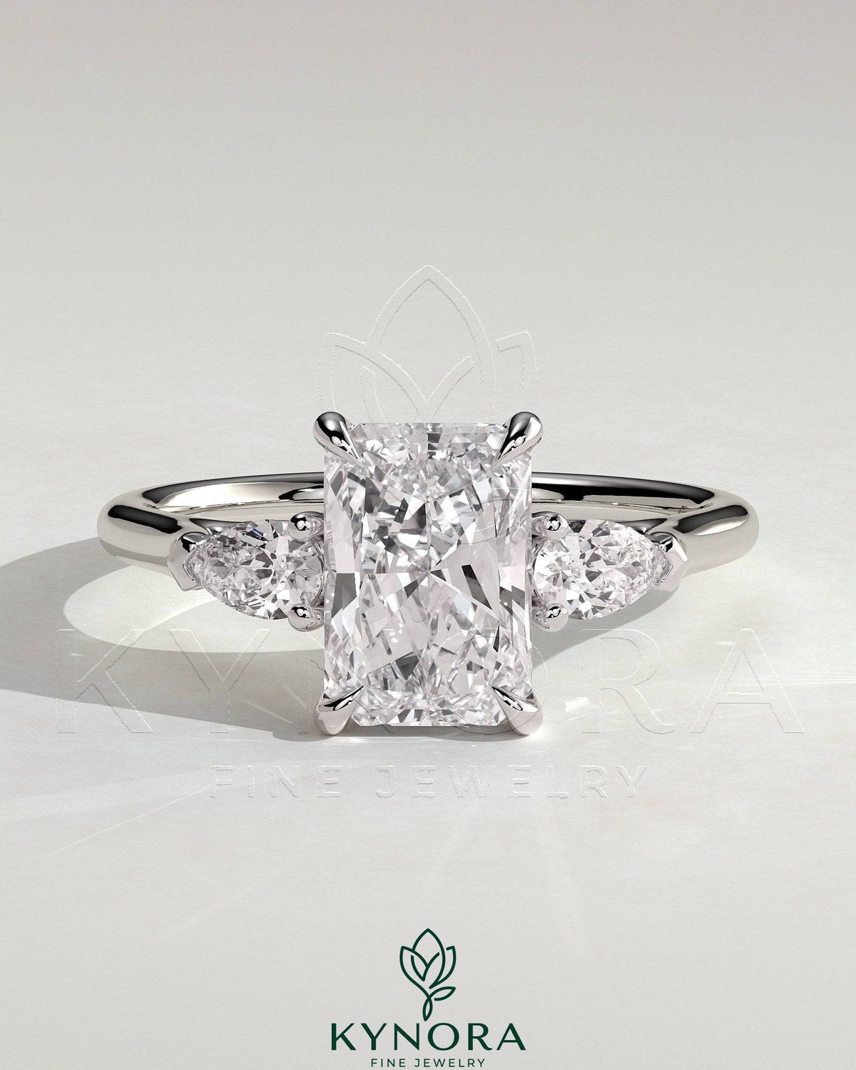 Kynora CJ 2ct radiant claw trilogy engagement ring with pear side stones and cathedral setting, showcasing intricate design.