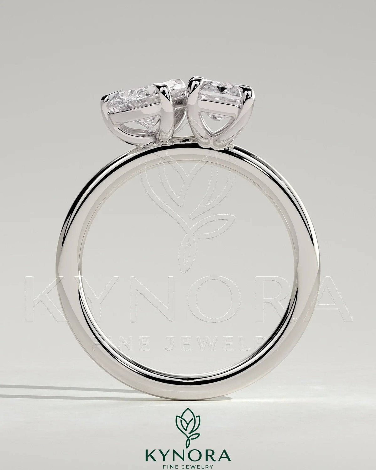 Kynora CJ 1.5ct pear-shaped and 1.8ct emerald-cut Toi et Moi engagement ring with claw setting, showcasing elegant gemstone design.