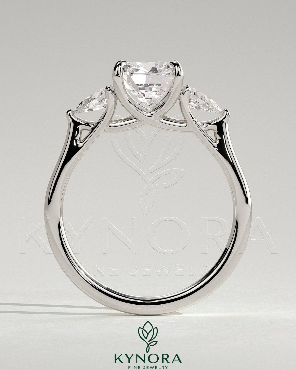 Kynora CJ cushion claw trilogy engagement ring with pear side stones and open trellis gallery design.