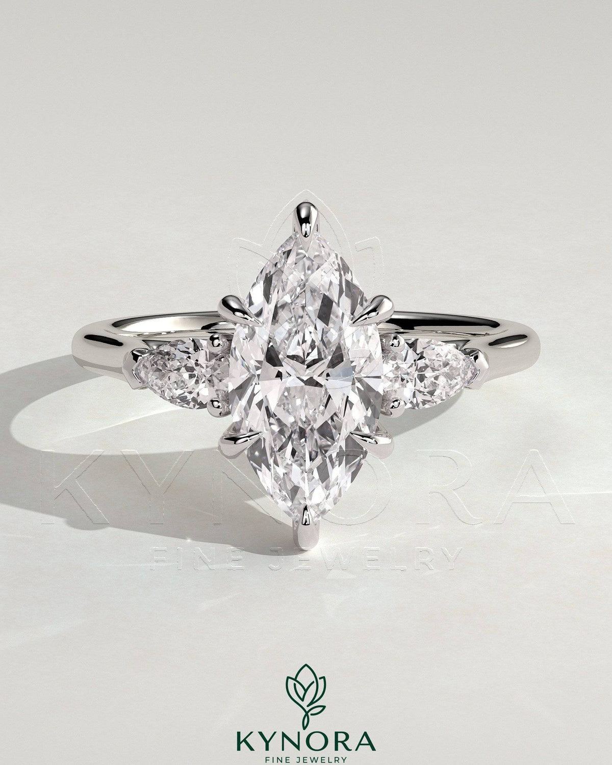 Kynora CJ three-stone engagement ring featuring 2ct marquise center stone, pear side stones, and cathedral setting in gold. Main image
