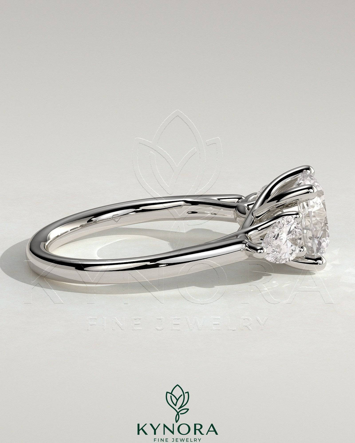 Kynora CJ 2ct round claw trilogy engagement ring with pear side stones and open trellis gallery design.