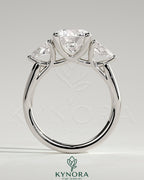 Kynora CJ 2ct three-stone engagement ring with round claw set center stone, pear side stones, and open trellis gallery design.
