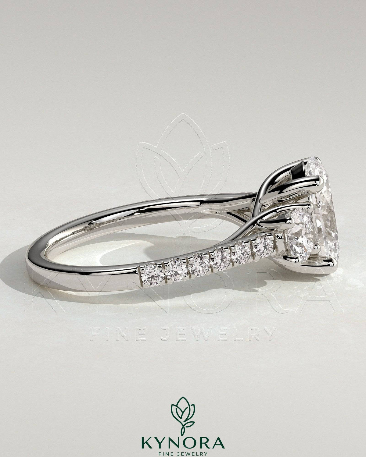 Kynora CJ 2ct oval claw trilogy engagement ring with round side stones, pave band, and trellis gallery design.