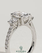 Kynora CJ 2ct oval claw trilogy engagement ring with round side stones, pave band, and trellis gallery design.
