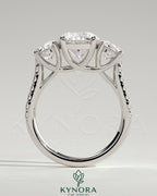 Kynora CJ 2ct round claw trilogy engagement ring with side stones, pave band, and trellis gallery design.