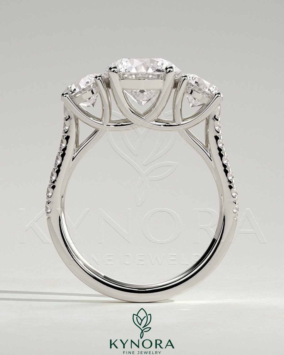 Kynora CJ 2ct round claw trilogy engagement ring with side stones, pave band, and trellis gallery design.