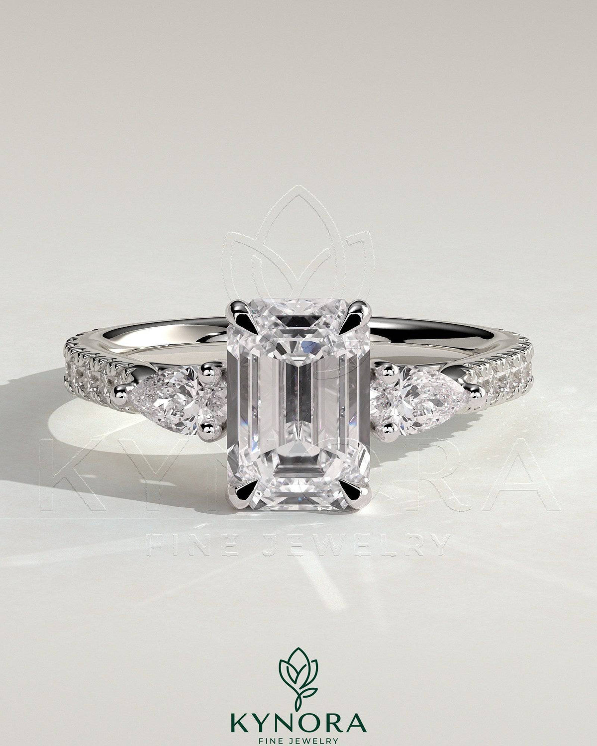 Kynora CJ 2ct emerald claw trilogy engagement ring with pear side stones and pave band, showcasing sparkling fine jewelry. Main image
