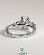Kynora CJ 2ct emerald claw trilogy engagement ring with pear side stones and pave band, showcasing elegant fine jewelry design.