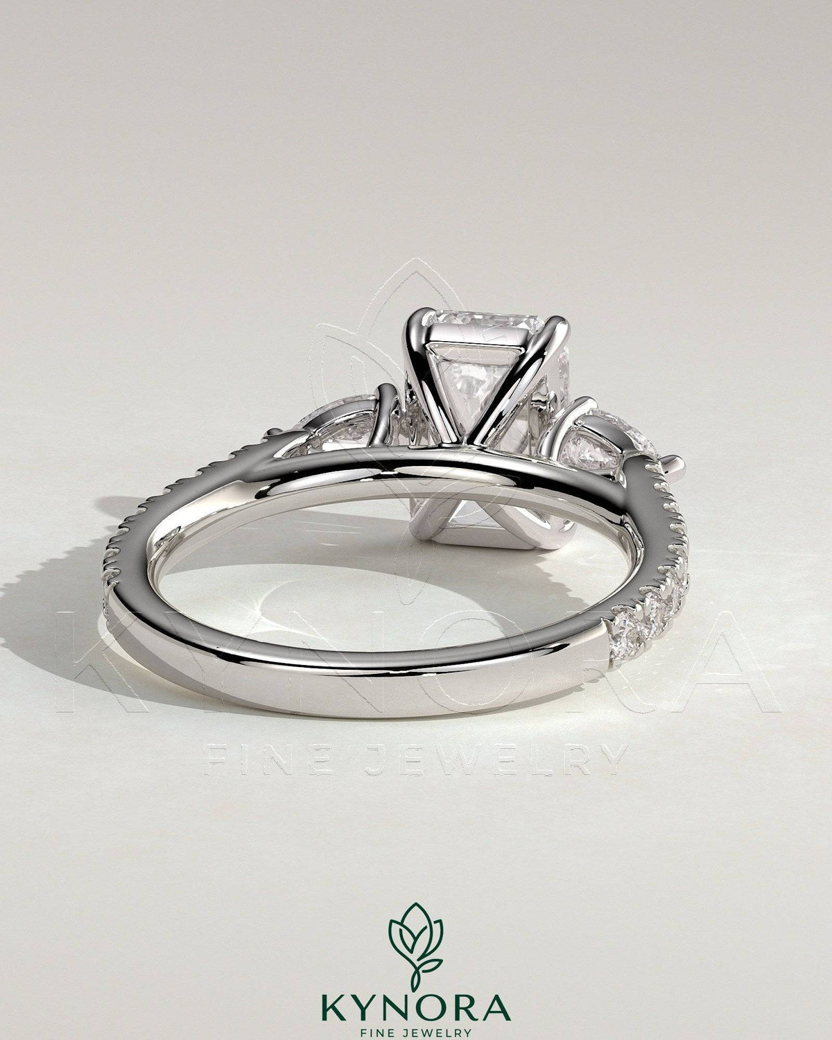 Kynora CJ 2ct emerald claw trilogy engagement ring with pear side stones and pave band, showcasing elegant fine jewelry design.