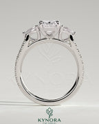 Kynora CJ 2ct emerald claw trilogy engagement ring with pear side stones and pave band, showcasing elegant diamond craftsmanship.