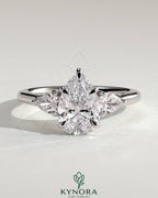 Kynora CJ three-stone engagement ring with 2-carat pear-shaped center diamond, side stones, and floating cathedral setting.
