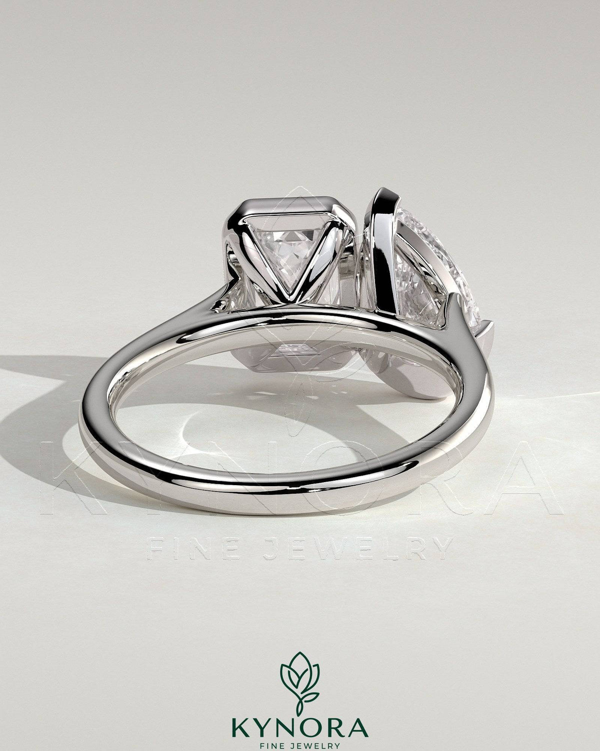 Kynora CJ Toi et Moi engagement ring with 3.3ct pear-shaped and 3.3ct emerald cut diamonds in bezel settings.