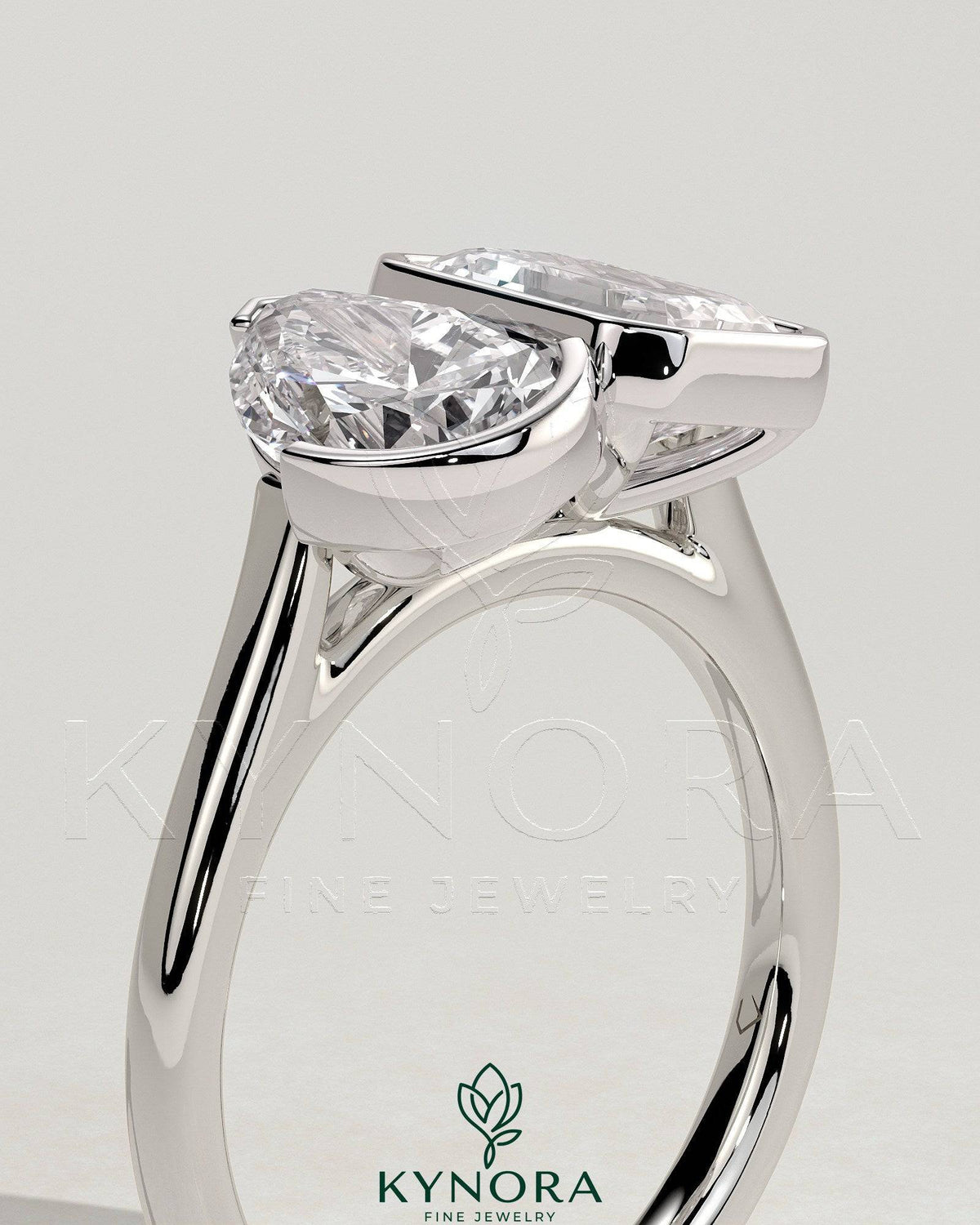 Kynora CJ 3.3ct pear-shaped and 3.3ct emerald-cut Toi et Moi engagement ring featuring bezel and half-bezel settings.