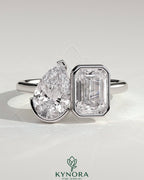Kynora CJ Toi et Moi engagement ring with 3.3ct pear-shaped and 3.3ct emerald-cut diamonds, bezel and half-bezel setting.