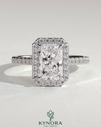 Kynora CJ 2ct radiant claw solitaire engagement ring with halo, pave band, and cathedral high setting showcasing sparkling diamond design.