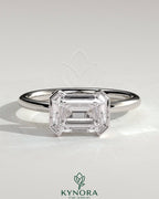 Kynora CJ 2ct emerald cut east-west bezel solitaire engagement ring with a sleek band and prominent gemstone display.
