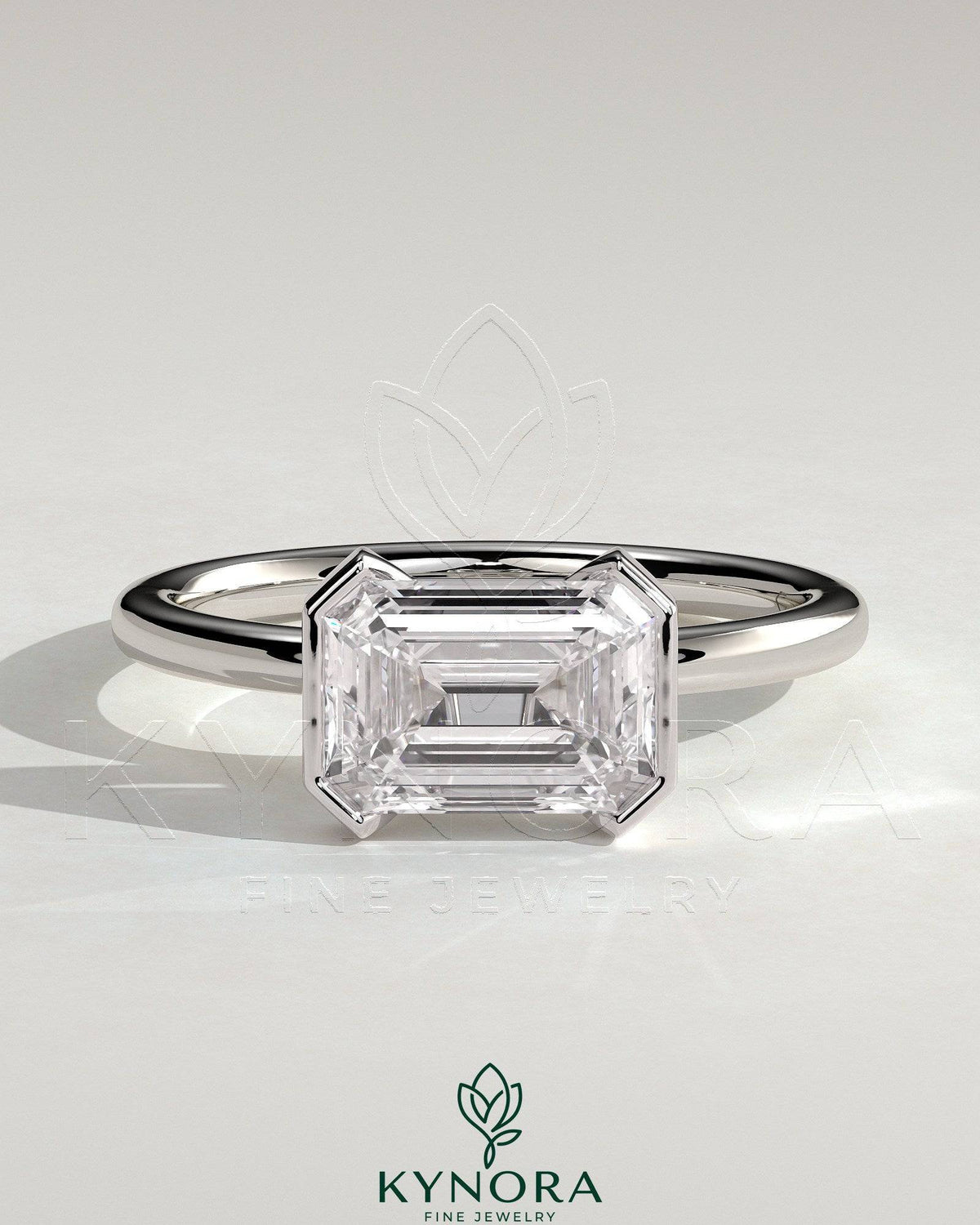 Kynora CJ 2ct emerald cut east-west bezel solitaire engagement ring with a sleek band and prominent gemstone display.