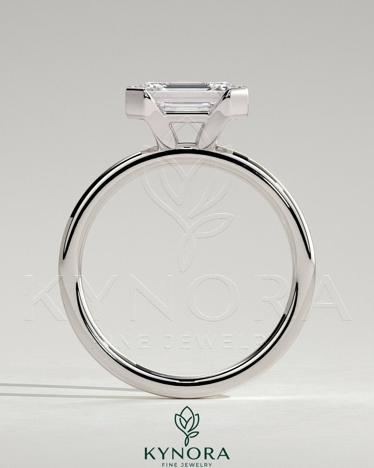 Kynora CJ 2ct emerald cut East-West bezel solitaire engagement ring showcasing a central emerald gemstone on a sleek band.