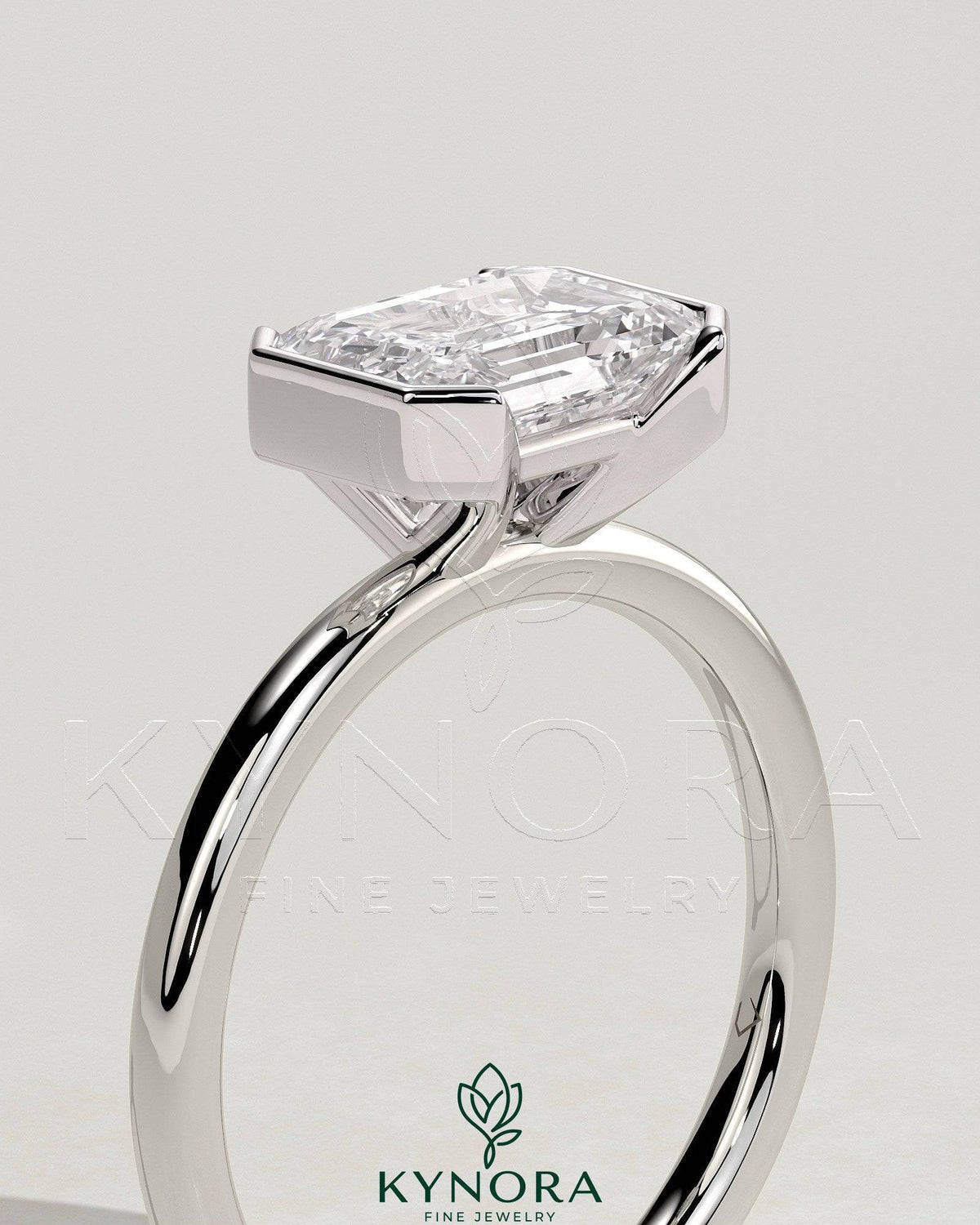 Kynora CJ 2ct emerald cut diamond engagement ring with east-west half bezel setting, showcasing elegant design and sparkling gemstone.