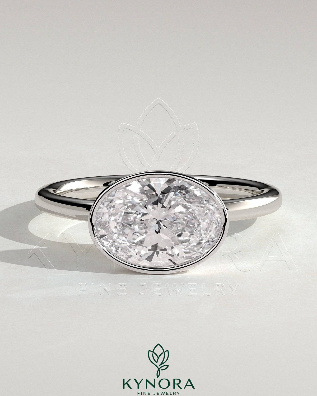 East-West 2-carat oval bezel solitaire engagement ring by Kynora CJ featuring a prominent oval diamond set horizontally on a sleek band