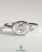 Kynora CJ 2ct oval east-west claw solitaire engagement ring with bezel frame, showcasing a sparkling central diamond on a sleek band.