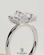 Kynora CJ 1.8ct emerald and 1.5ct pear-shaped diamond Toi et Moi engagement ring with hidden halo setting and intricate band details.
