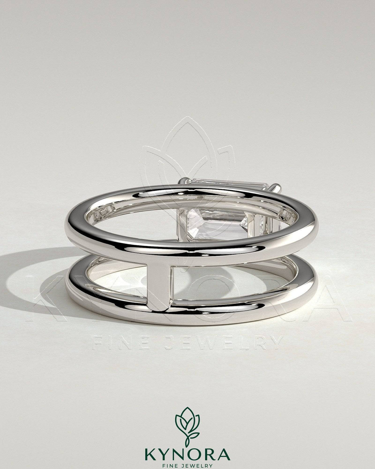 Kynora CJ 2ct emerald east-west claw solitaire engagement ring with spaced double band, showcasing a vibrant green emerald and elegant design.