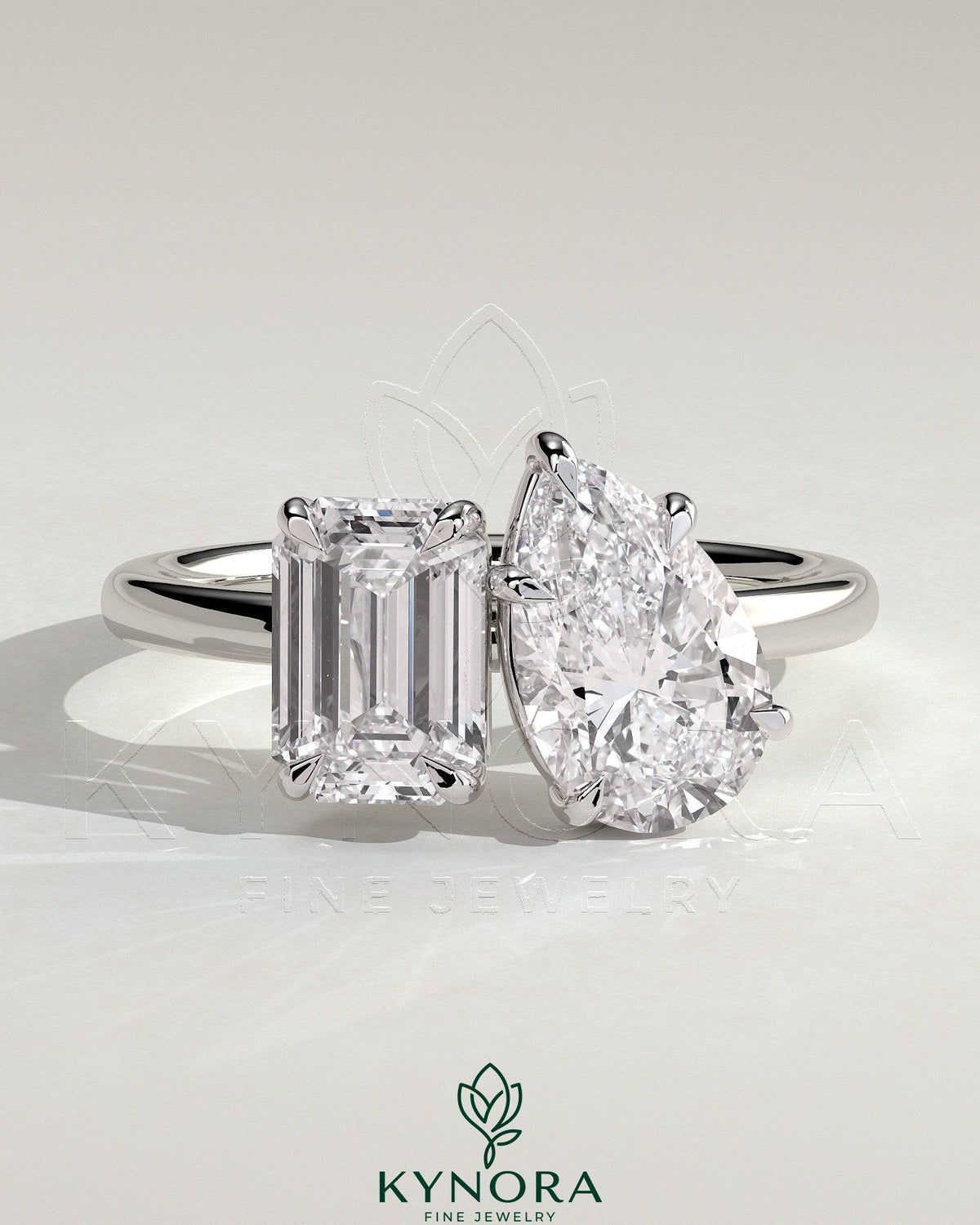 Kynora CJ 1.8ct emerald and 1.5ct pear-shaped diamonds Toi et Moi engagement ring with hidden halo and claw setting.