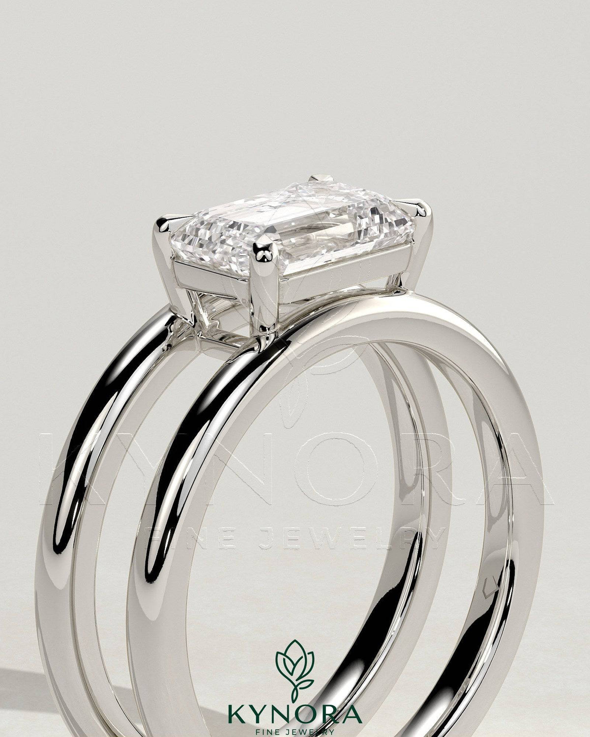 Kynora CJ 2ct emerald east-west claw solitaire engagement ring with a spaced double band, showcasing a stunning emerald gemstone.
