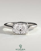 Kynora CJ 2ct elongated cushion cut East-West claw solitaire engagement ring with bezel frame showcasing a sparkling diamond.