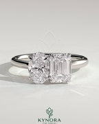 Kynora CJ Toi et Moi engagement ring featuring a 1.05ct oval and 1.8ct emerald-cut diamonds set in a gold band.