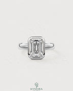 Emerald cut moissanite bezel engagement ring in 925 silver with a sleek band, designed by Kynora CJ.