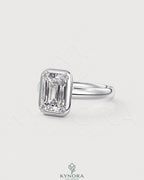 Emerald cut moissanite bezel engagement ring in 925 silver with a sleek, modern design by Kynora CJ.