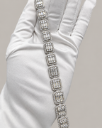 Sterling silver tennis bracelet with baguette stones, stylish hip-hop jewelry by Kynora Jewels on a white glove.