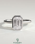 Kynora CJ 2ct emerald bezel solitaire engagement ring with cathedral high setting showcasing a vibrant green emerald gemstone.