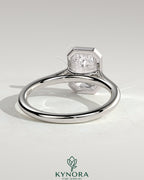 Kynora CJ 2-carat emerald bezel solitaire engagement ring with cathedral high setting, showcasing a sparkling emerald gemstone and elegant design.