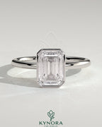 Kynora CJ 2ct emerald bezel solitaire engagement ring with petal gallery design, showcasing a central emerald-cut stone in a detailed setting.