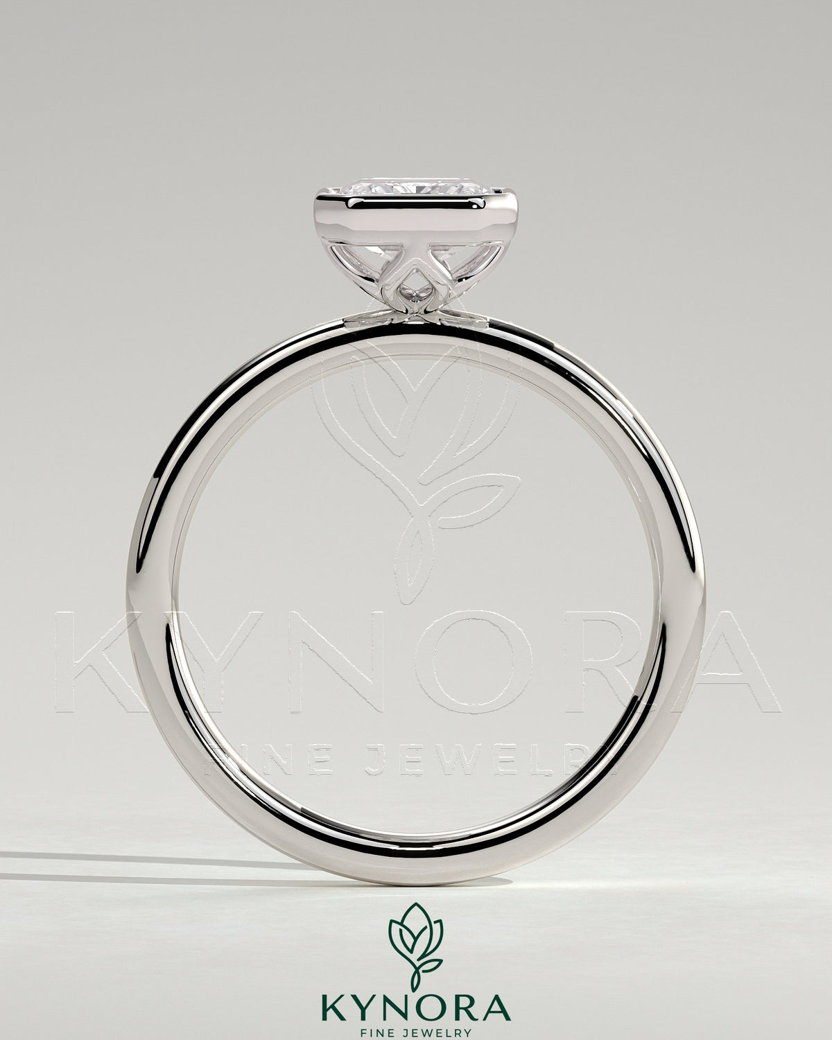 Kynora CJ 2ct emerald bezel solitaire engagement ring with petal gallery design, featuring a central emerald-cut gemstone in a delicate band.