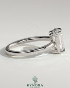 Kynora CJ 2ct emerald claw solitaire engagement ring with bezel frame, showcasing a vibrant green emerald gemstone and sleek metal band.