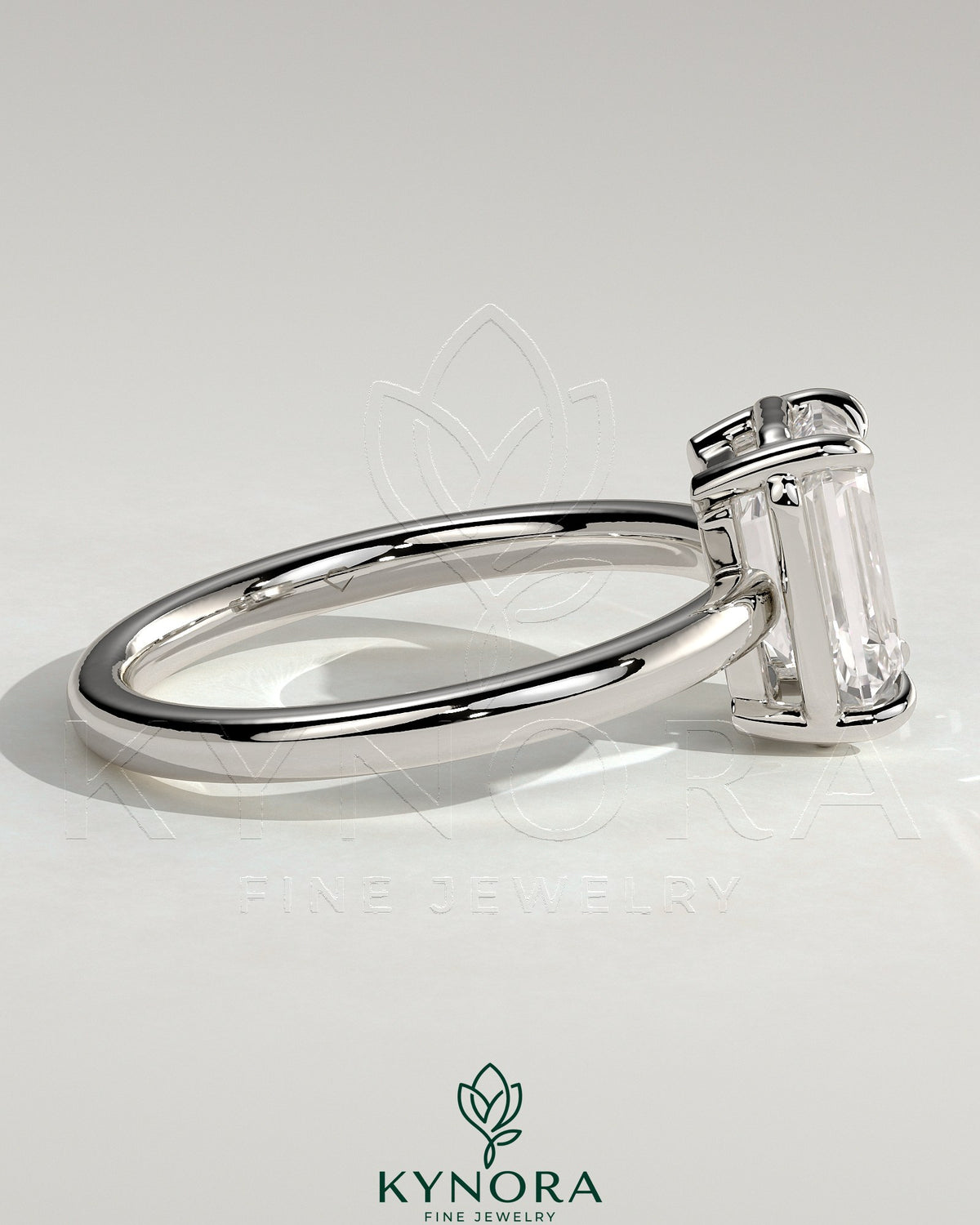 Kynora CJ 2ct emerald claw solitaire engagement ring with bezel frame, showcasing a vibrant green emerald gemstone and sleek metal band.