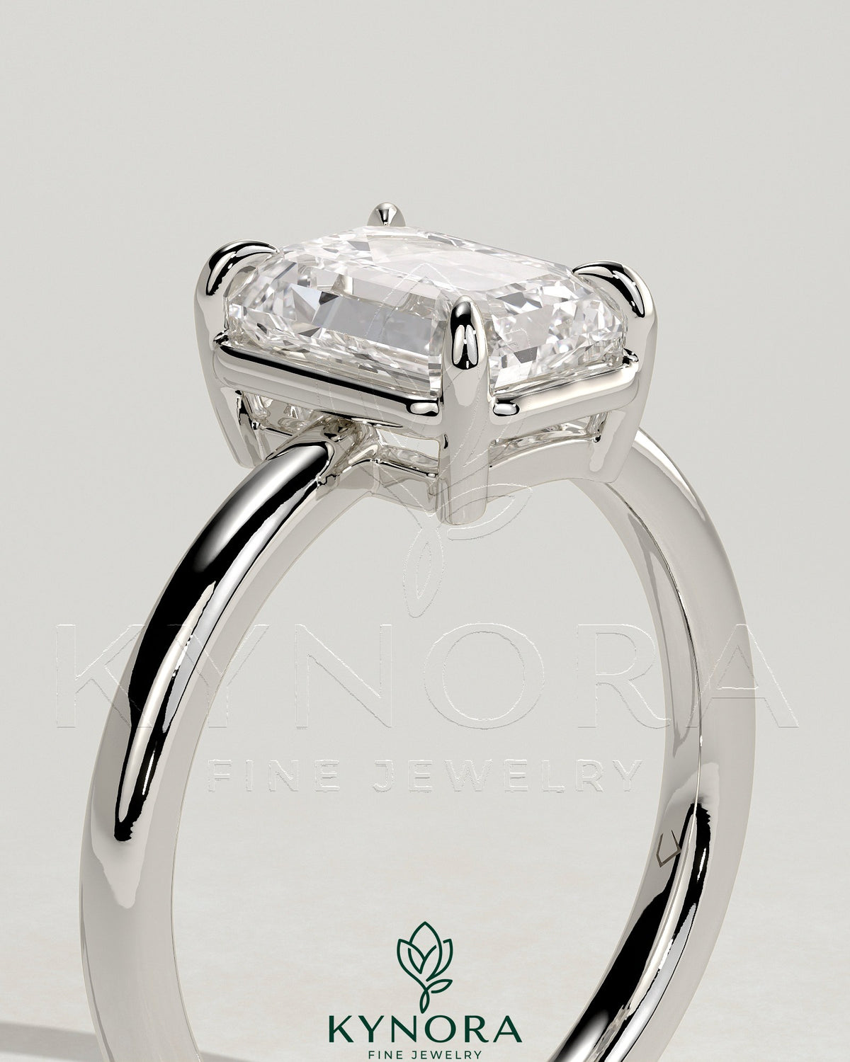 Kynora CJ 2ct emerald claw solitaire engagement ring with bezel frame, showcasing a vibrant green emerald gemstone and elegant metal setting.