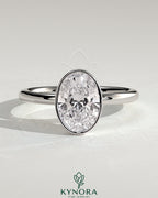 Kynora CJ 2ct oval bezel solitaire engagement ring with a sleek band and central oval diamond setting.