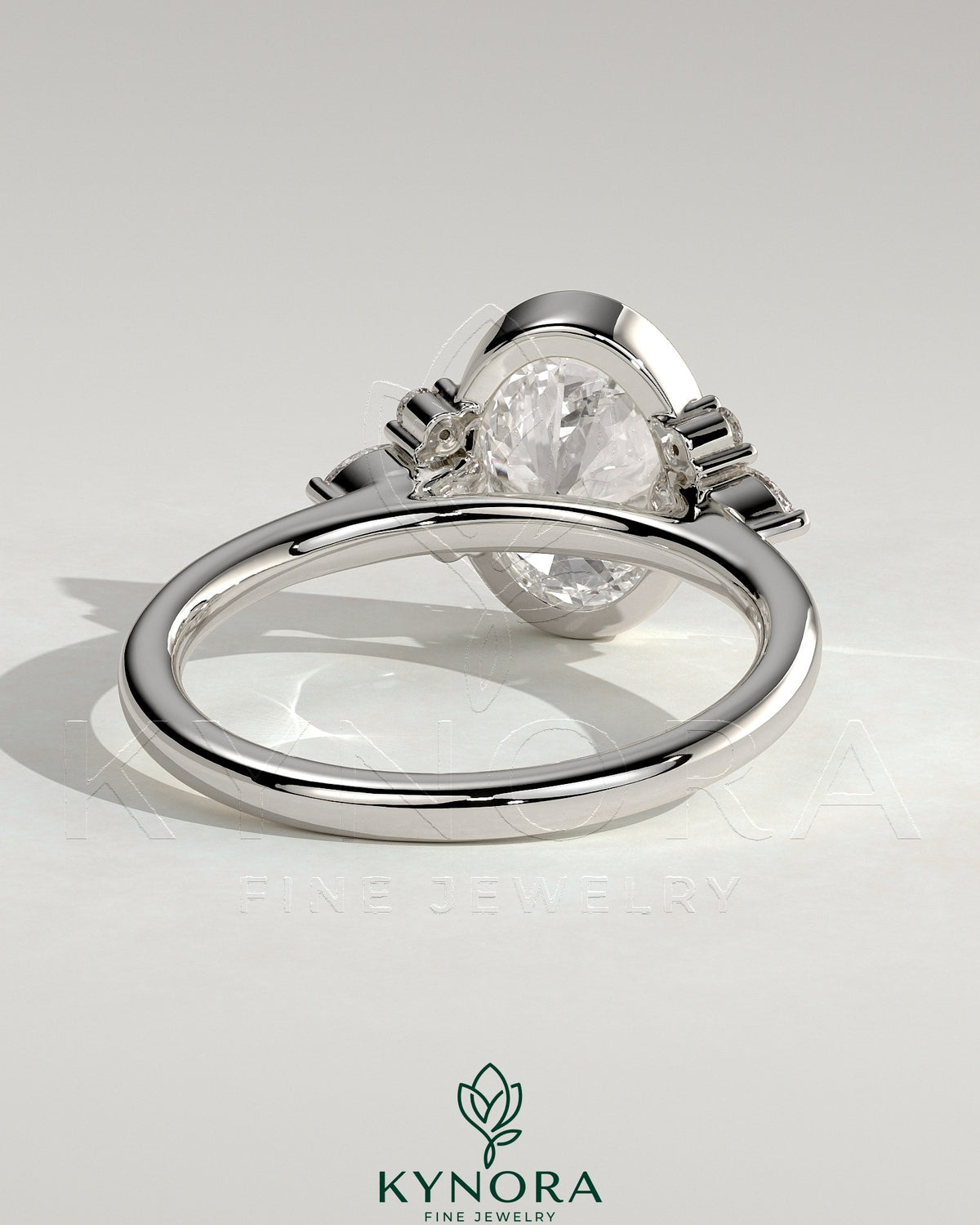 Kynora CJ 2ct oval bezel solitaire engagement ring with marquise and round shoulder stones in a cathedral high setting.