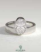 Kynora CJ 2ct oval bezel solitaire engagement ring with offset setting and flat cigar band, showcasing elegant jewelry design.