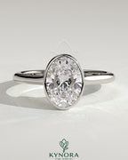 Kynora CJ 2ct oval bezel solitaire engagement ring with twisted gallery design, featuring a sparkling central stone and intricate band details.