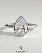 Kynora CJ 2ct pear-shaped diamond bezel solitaire engagement ring with cathedral high setting and intricate metalwork.
