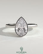 Kynora CJ 2ct pear-shaped bezel solitaire engagement ring with hidden halo and cathedral high setting, showcasing elegant diamond design.